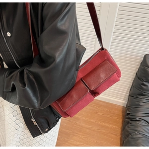 Detail of burgundy faux suede baguette bag with dual front flap pockets and slim strap
