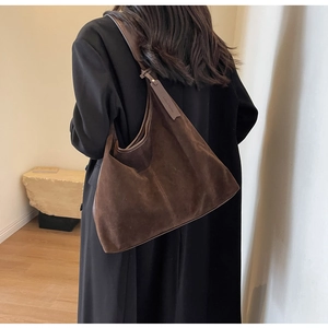 Detail of soft brown suede shoulder bag showing fine stitching and leather brand tag