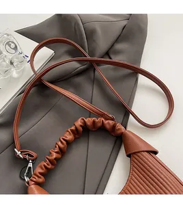 Detail of a brown leather crescent bag with pleated texture and stylish gathered handle