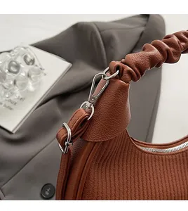 Detail of silver metal buckle and pleated leather handle on dark brown dumpling bag
