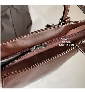 Detail of smooth metal zipper and white contrast stitching on vintage brown leather tote bag