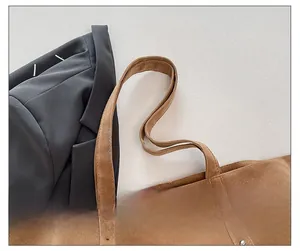 Détail d'un sac cabas en daim marron avec rivets argentés et longue bandoulière réglable