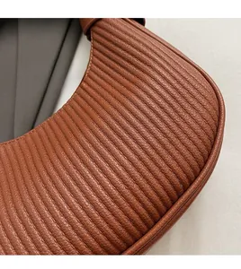 Detail shot of brown pleated texture and neat stitching on a vintage crescent shoulder bag