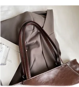 Close-up of vintage brown leather tote bag handles with white contrast stitching