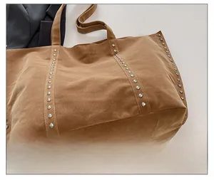 Détail d'un sac cabas en daim marron avec des décorations en rivets argentés et texture