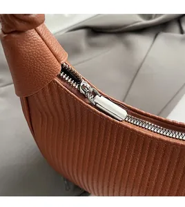 Detailed macro view of a silver metal zipper on premium brown lychee texture leather bag