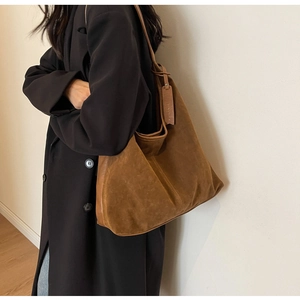 Detail of vintage brown suede tote bag featuring fine stitching and leather shoulder strap