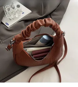 Spacious interior of brown pleated crescent bag showing capacity for phone and cosmetics