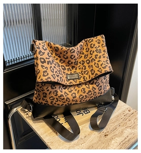 Detail of leopard print canvas bag with black leather trim and brand logo on marble