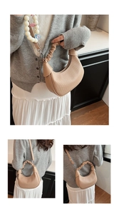 Close-up of beige pleated crescent bag with scrunched handle and bead charm detail