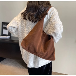 Detailed view of the large dark brown suede tote bag worn on shoulder by a model