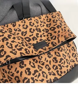 Detail of leopard print fabric texture and premium leather stitching on the backpack