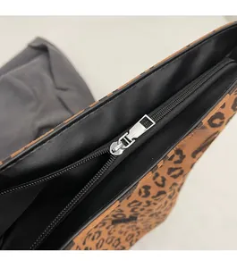 Close-up of smooth silver metal zipper and leopard print fabric with leather edging