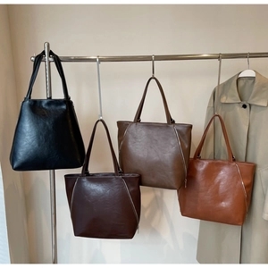 Various colors of vintage leather tote bags hanging on a metal rack in a studio