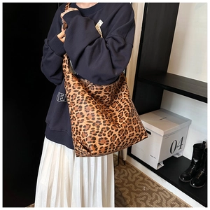 Lifestyle shot of large leopard print canvas bucket bag worn as a shoulder hobo bag