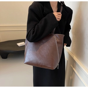 Detail shot of brown vintage tote bag showing texture and white contrast stitching