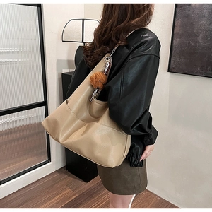 Detail view of khaki PU leather tote bag with side pocket and brown teddy bear charm
