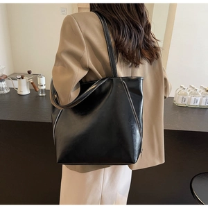 Detail of vintage black leather tote bag with white contrast stitching and side zipper