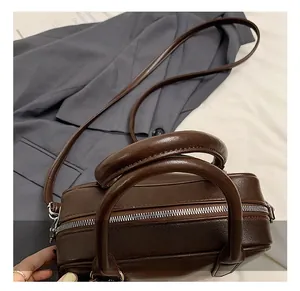 Detail view of dark brown PU leather boston bag with top handle and stitching