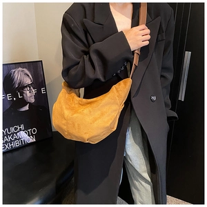 Détail d'un sac demi-lune jaune moutarde en daim avec une fine bandoulière en cuir