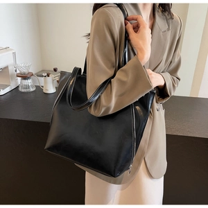 Detail of black tote bag with white contrast stitching and metallic side zipper