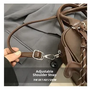 Close-up of the adjustable leather shoulder strap with silver metal buckle on a brown bag