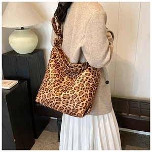 Detailed close-up of large leopard print tote bag with gold metal rings and knot detail