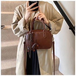 Brown vintage Boston bag with cute charms shown as a crossbody on a female model