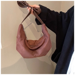 Gros plan d'un sac hobo en daim marron montrant sa forme demi-lune et ses surpiqûres