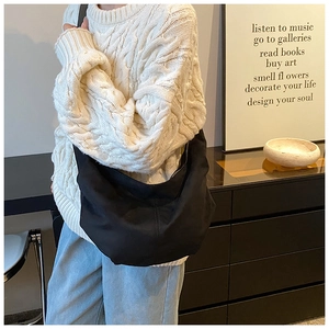 Sac demi-lune minimaliste en daim noir porté avec un pull en maille pour look d'automne