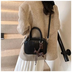 Model view of a black leather Boston bag with a cute puppy charm and woven rope detail