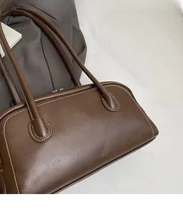 Close-up of deep brown leather bag showing premium texture and contrast white stitching