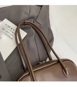 Detail of reinforced shoulder straps on brown leather tote with white contrast stitching