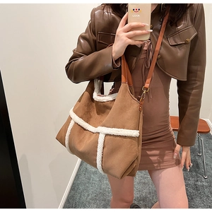 Detail of brown suede tote bag with white shearling trim and premium leather handles