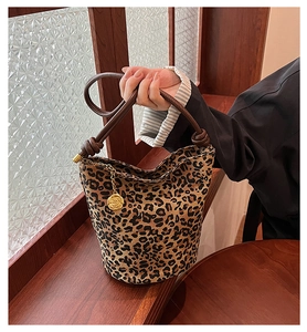 Detail of leopard print bucket bag featuring leather knot handle and gold rose pendant