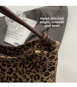 Close-up of leopard print bucket bag featuring brown leather knotted strap and gold hardware