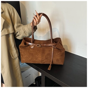 Detail of a brown suede tote bag with contrast leather straps and adjustable buckles
