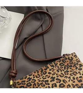 Detail of leopard print bucket bag featuring brown knotted strap and gold hardware