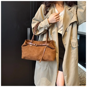 Detail of caramel brown suede tote bag featuring leather handles and decorative belt strap