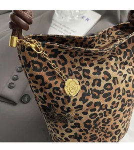 Macro detail of leopard print canvas bag with braided handle and gold camellia charm