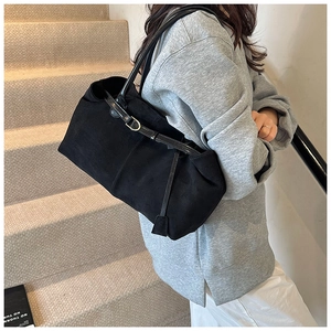 Close-up of black matte tote bag with golden metal buckle and sleek leather straps