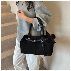 Detail of matte texture black tote bag with glossy leather strap and metal buckle detail