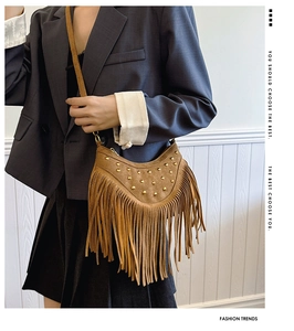 Détail du sac à franges en daim avec clous dorés porté par un mannequin en blazer