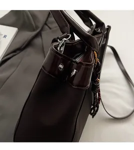 Detail of dark brown leather handbag with silver metal buckles and woven rope charm decor