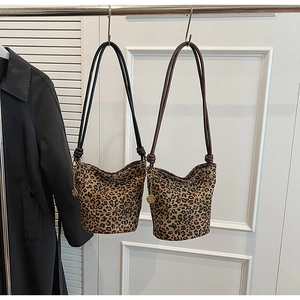 Detail of leopard print canvas bucket bag with rope handles and golden rose charm