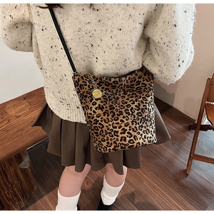 Close-up of leopard print bucket bag with golden flower charm on beige knit sweater