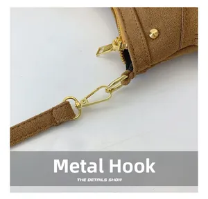 Détail des crochets dorés et des rivets sur un sac à bandoulière en daim marron
