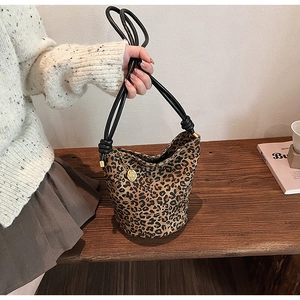 Close-up of leopard print bucket bag with black knotted handles and golden charm detail