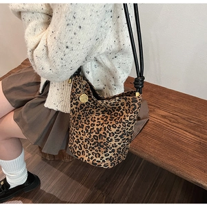 Detail of leopard print bucket bag with golden rose charm and knot strap on model