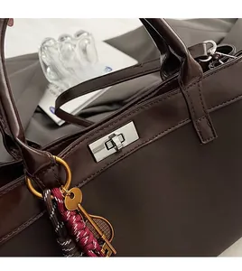 Detail of dark brown leather handbag with silver twist lock and decorative key charm
